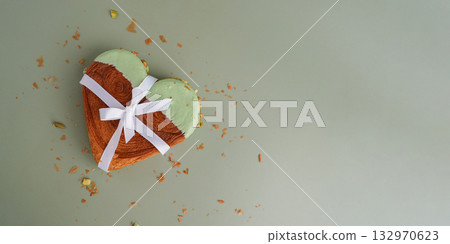 Present gift ribbon Delicious fresh croissant topped with Matcha Green Tea flavor Ganache. Creation unique heart shape bakery. Puff pastry holiday love symbol idea Valentine's day 132970623