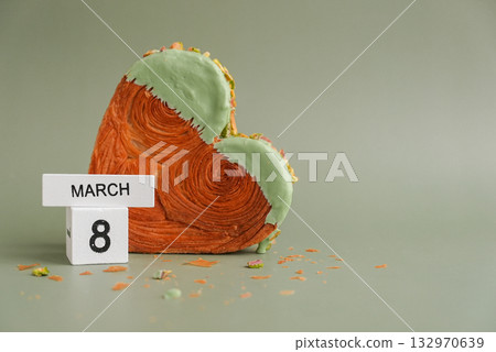 8 March Women's day Female holiday greeting card Heart shaped pistachio croissant on green background with copy space. Puff pastry new trendy sweet dessert bakery. Creamy dough 132970639