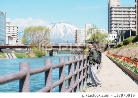 man tourist sightseeing Iwate mountain and Kitakami river with flowers in Spring, happy traveler travel in Morioka city, Iwate prefecture, Japan. famous Landmark Travel and Vacation destination man tourist sightseeing Iwate mountain and Kitakami river with flowers in Spring, happy traveler travel in Morioka city, Iwate prefecture, Japan. famous Landmark Travel and Vacation destination 132970919