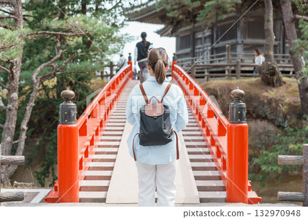 Woman tourist walking cross Sukashibashi bridge to the Zuiganji Godaido or National Treasure, a temple building on a small island in Matsushima Bay in Matsushima, Miyagi Prefecture, Tohoku, Japan 132970948