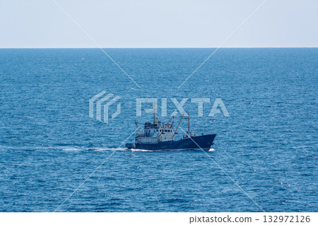 Fishing boat in blue sea and clear sky with birds flying overhead. Fishing boat in blue sea and clear sky with birds flying overhead. 132972126