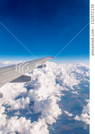 View from the airplane window at a beautiful cloudy sky and the airplane wing View from the airplane window at a beautiful cloudy sky and the airplane wing 132972139