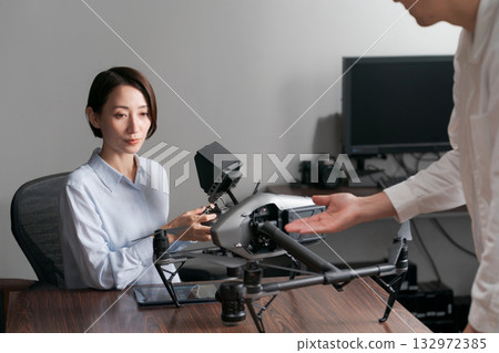 A woman receiving instruction on how to operate a drone 132972385