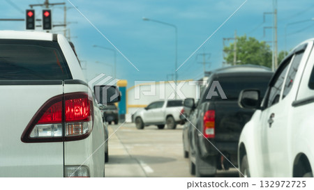 Rear side of pickup white car stop or parking on the road. Turn on brake light in the junction from traffic red light control with other cars. Car on the right drives through first. Under blue sky. 132972725