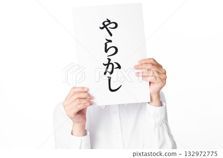 A person wearing a white shirt holding a piece of paper with the word "Yarakashi" written on it A person wearing a white shirt holding a piece of paper with the word "Yarakashi" written on it 132972775