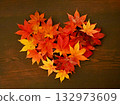Heart-shaped autumn leaves and wood grain background 132973609