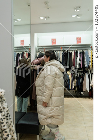 Woman Trying on Coat in Clothing Store Woman Trying on Coat in Clothing Store 132974405