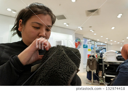 Woman Inspecting Clothing in Store 132974418