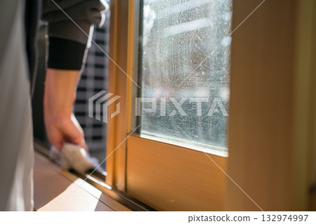 A housewife cleaning the window sash rails 132974997