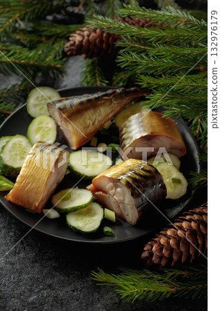 Smoked mackerel with fresh cucumber and green onions on a black plate. 132976179