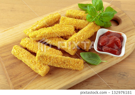 Fish fingers with basil and ketchup on a wooden table. 132976181