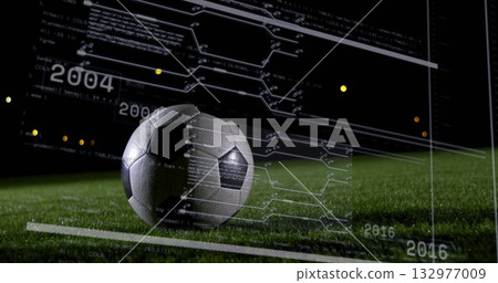 Resting soccer ball displaying digital data overlay on grass turf at night, with code metrics 132977009