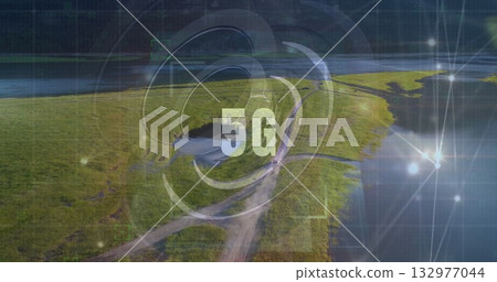 Radiating digital 5G graphic sending connectivity rings over riverside marshland, with dirt road 132977044