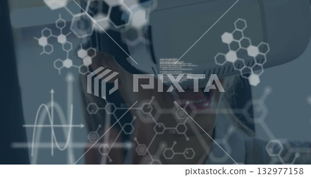 Reacting woman wearing jacket and VR headset in tech studio, molecular holograms, graph overlays 132977158