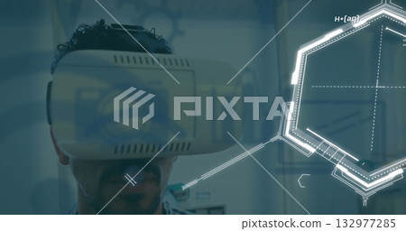 Mid adult man wearing VR headset exploring holographic interface in tech lab, with data labels Mid adult man wearing VR headset exploring holographic interface in tech lab, with data labels 132977285