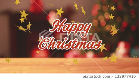 Showing text reading Happy Christmas on wooden tabletop at home, with golden stars and blurred tree 132977410