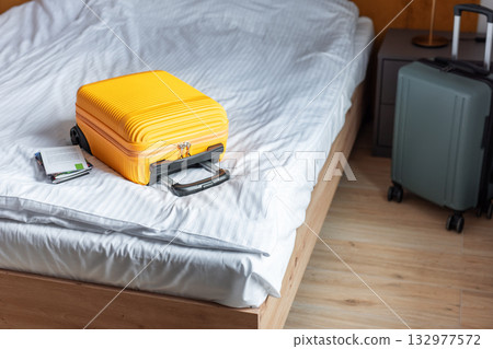 Orange suitcase on hotel bed welcoming travelers arrival Orange suitcase on hotel bed welcoming travelers arrival 132977572