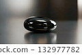 Single black zen stone with smooth shiny surface on reflective background. Minimalist concept for spa wellness or meditation. Symbol of balance harmony and relaxation. Calm abstract nature 132977782
