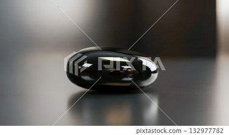 Single black zen stone with smooth shiny surface on reflective background. Minimalist concept for spa wellness or meditation. Symbol of balance harmony and relaxation. Calm abstract nature 132977782