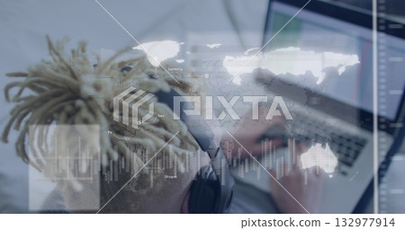 Typing man with dreadlocks wearing headset typing on laptop at home, with world map, chart overlays Typing man with dreadlocks wearing headset typing on laptop at home, with world map, chart overlays 132977914