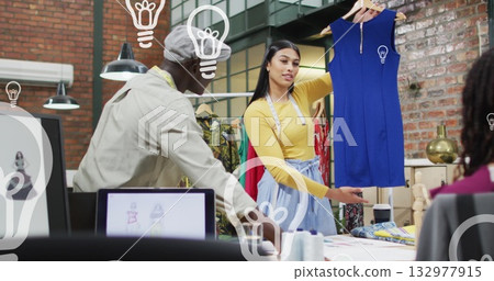 Female designer holding blue dress in loft studio, colleague offering feedback with fabric swatches Female designer holding blue dress in loft studio, colleague offering feedback with fabric swatches 132977915