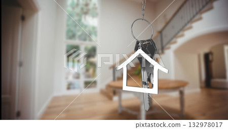 Hanging metal keyring with house-shaped keychain pendant and keys swinging gently in modern foyer Hanging metal keyring with house-shaped keychain pendant and keys swinging gently in modern foyer 132978017