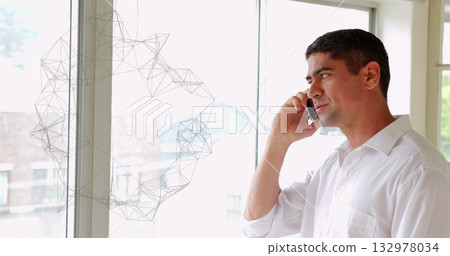 Mature man wearing white shirt talking on smartphone in office beside wireframe window, copy space 132978034