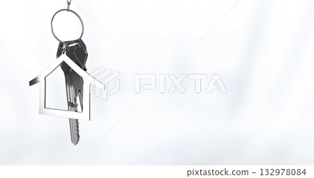 Hanging silver keyring swaying on white backdrop with metal keys and house-shaped charm, copy space Hanging silver keyring swaying on white backdrop with metal keys and house-shaped charm, copy space 132978084