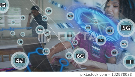 Typing curly-haired woman leaning over laptop at office desk, digital network graphics, copy space 132978088