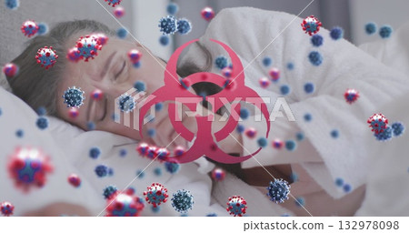Resting woman lying in bed, holding tissue with virus particles and biohazard symbol 132978098