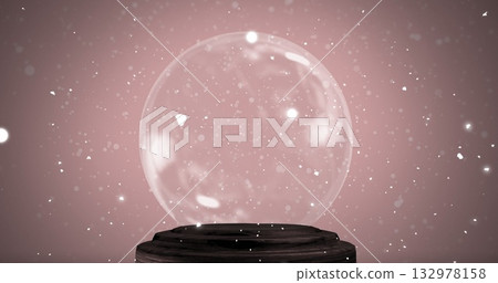 Displaying transparent glass sphere resting on dark wooden pedestal in studio, with white particles 132978158