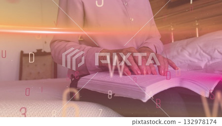 Reading senior woman turning book pages on bed at home, with digital letter and number overlays 132978174
