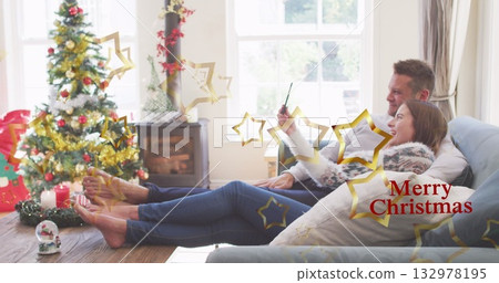 Reclining couple in sweaters taking selfie in Christmas living room, with tree, stove, copy space Reclining couple in sweaters taking selfie in Christmas living room, with tree, stove, copy space 132978195