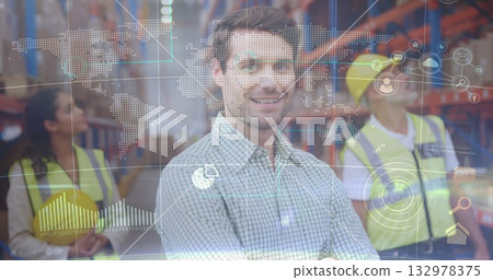 Smiling supervisor standing at distribution center with racks workers holding helmets under overlay 132978375