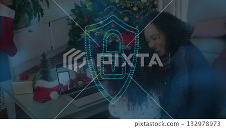 Mother and child sharing laptop call in living room, with Christmas tree and digital shield Mother and child sharing laptop call in living room, with Christmas tree and digital shield 132978973