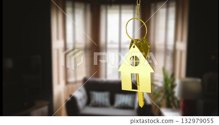 Hanging golden key ring with house-shaped keychain and keys in living room, with sofa and lamp 132979055