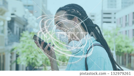 Holding smartphone, man wearing white earbuds examining augmented reality on pedestrian street 132979261