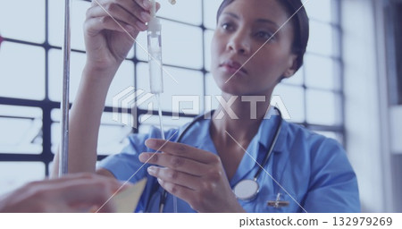 Nurse in blue scrubs with stethoscope adjusting drop chamber and regulator on metal stand in clinic Nurse in blue scrubs with stethoscope adjusting drop chamber and regulator on metal stand in clinic 132979269