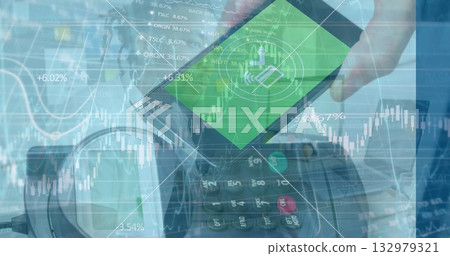 Holding smartphone showing payment icon hovering over card reader at checkout with financial charts Holding smartphone showing payment icon hovering over card reader at checkout with financial charts 132979321