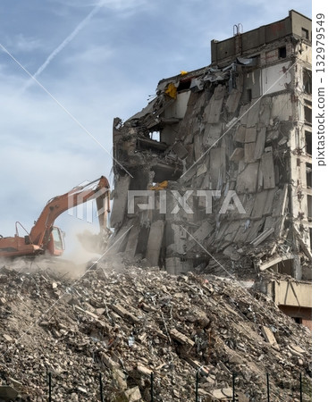 Excavator demolishes concrete building as dust and rubble rise at a demolition site Excavator demolishes concrete building as dust and rubble rise at a demolition site 132979549