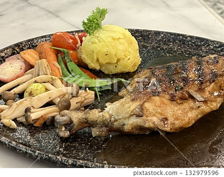 Grilled chicken steak with sauce, mushrooms and vegetables on a black plate 132979596