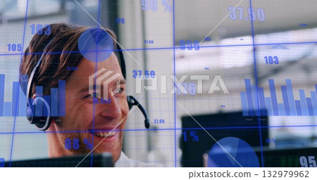 Smiling adult man wearing headset analyzing data charts at office desk, with computer Smiling adult man wearing headset analyzing data charts at office desk, with computer 132979962
