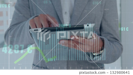 Tapping tablet businessman wearing grey suit and white shirt in office, with financial charts Tapping tablet businessman wearing grey suit and white shirt in office, with financial charts 132980641