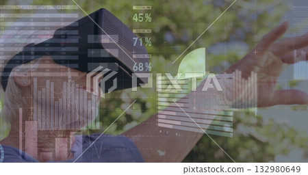 Senior woman wearing blue shirt and VR headset touching digital graphs in garden, copy space Senior woman wearing blue shirt and VR headset touching digital graphs in garden, copy space 132980649