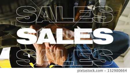 Inspecting mechanic wearing blue coverall working beneath car at workshop, with hydraulic lift arms 132980664