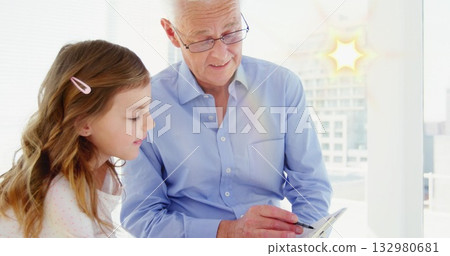 Guiding man wearing glasses and girl focusing on tablet at table beside sunlit window, stylus 132980681