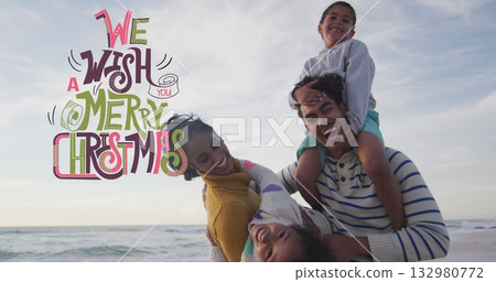 Laughing parents holding children on sandy beach, with Christmas graphic overlay, copy space 132980772
