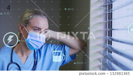 Gazing nurse scanning digital grid through blinds at medical facility, with mask and stethoscope Gazing nurse scanning digital grid through blinds at medical facility, with mask and stethoscope 132981365