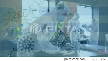 Cleaning technician in white coverall wiping desk at office workspace, with spray bottle and cloth 132981397