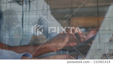 Collaborating coworkers interacting with tablet and typing on laptop keyboard at desk, with charts 132981414